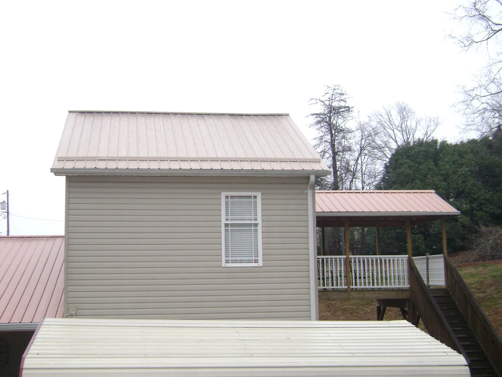 Tan metal roofs on a two story addition and attached porch, from a Roof Replacement job in Cowiche