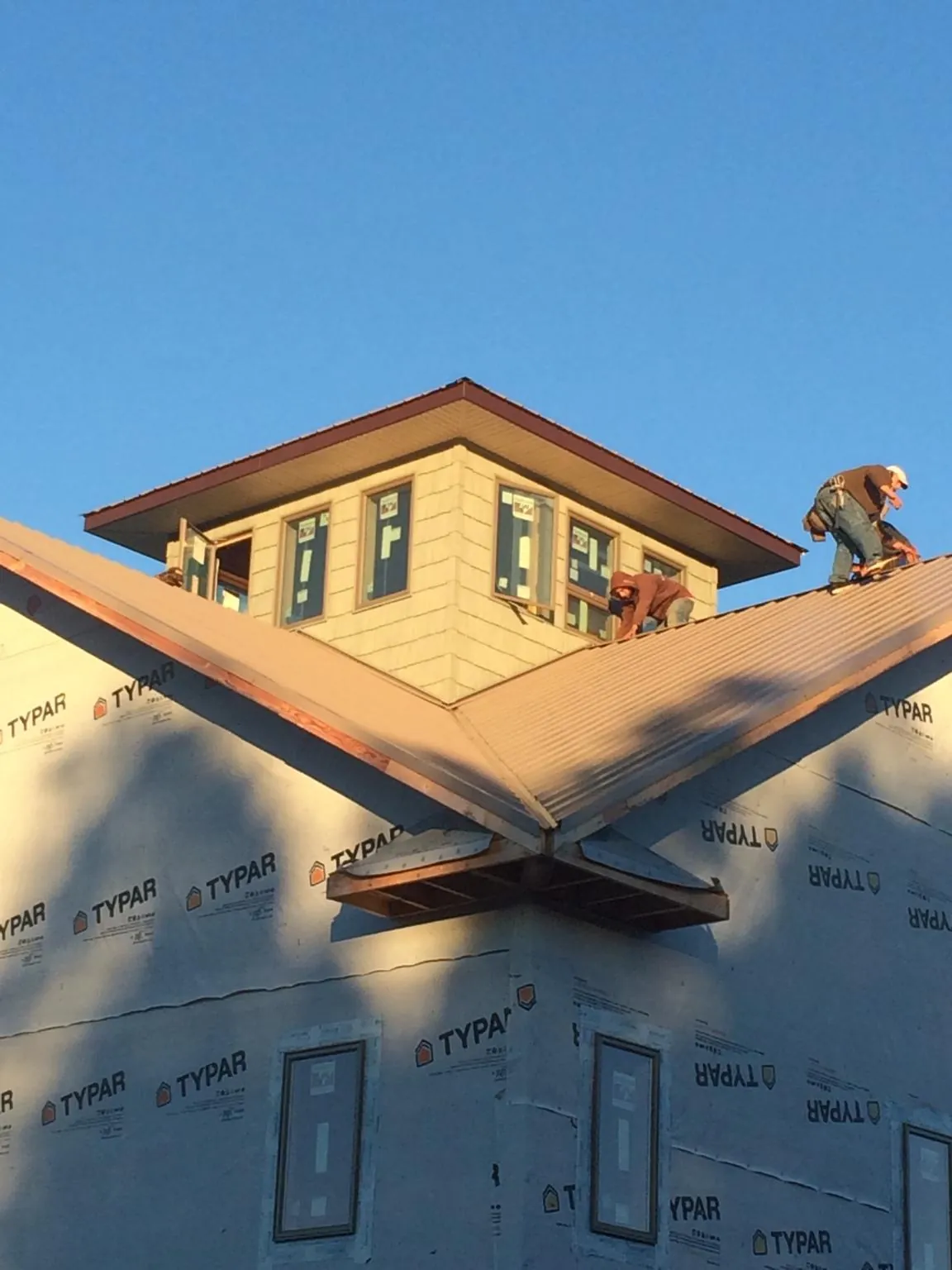 Roofers working around a rooftop cupola on a new metal roof at sunset — Roof Waterproofing in Cowiche by Roofing Brothers